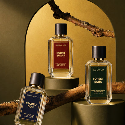 Three perfume bottles labeled 'Burnt Sugar', 'Forest Echo', and 'Sacred Oud' on a decorative background.